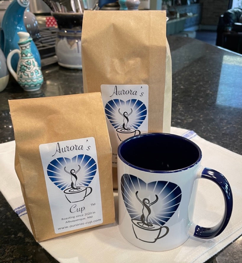 Two bags of Aurora's Cup Coffee with a branded mug in the foreground.